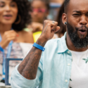 a man with a beard and a blue wristband raising his fist