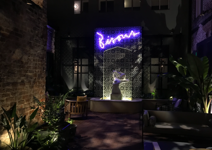 a courtyard with a statue and a purple neon sign