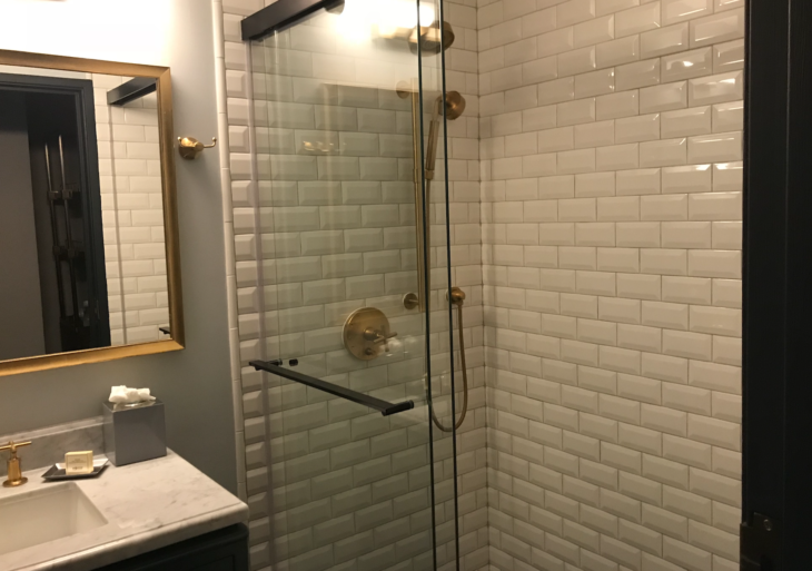 a glass shower with a gold handle