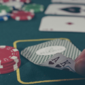 a hand holding cards next to poker chips