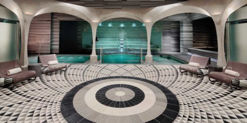 a pool with a circular pattern floor and a pool with a stone wall