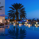 a pool with palm trees and a building with lights