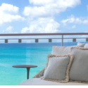 a couch with pillows on a balcony overlooking the ocean