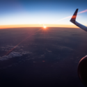 an airplane wing and the sun above the clouds