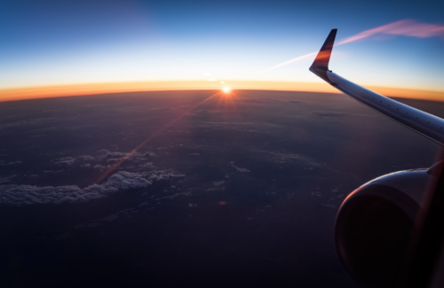 an airplane wing and the sun above the clouds