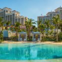 a pool with palm trees and buildings in the background