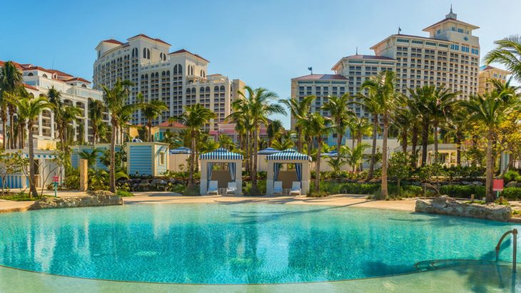 a pool with palm trees and buildings in the background