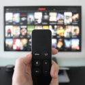 a hand holding a remote control in front of a television