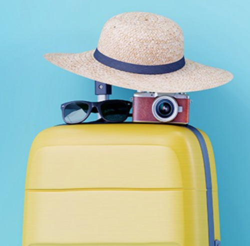 a yellow suitcase with a hat and sunglasses on top