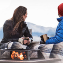 a man and woman sitting on a couch with a fire pit