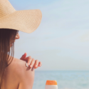a woman wearing a hat and holding a sun cream