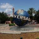 a large globe fountain in front of a roller coaster