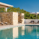 a pool with chairs and a stone wall