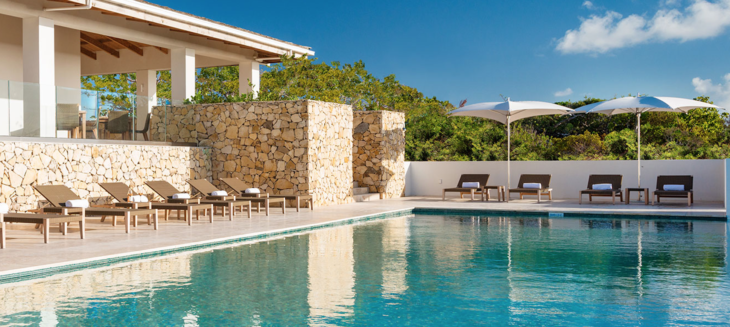 a pool with chairs and a stone wall