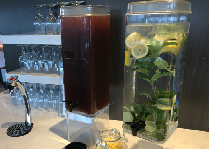 a water dispenser with a brown liquid and a brown plant in it