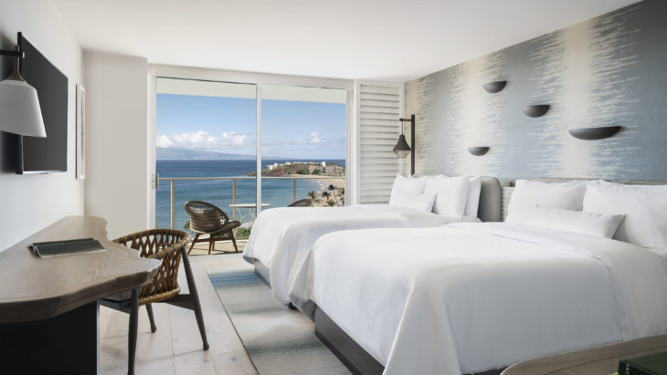 a room with two beds and a view of the ocean