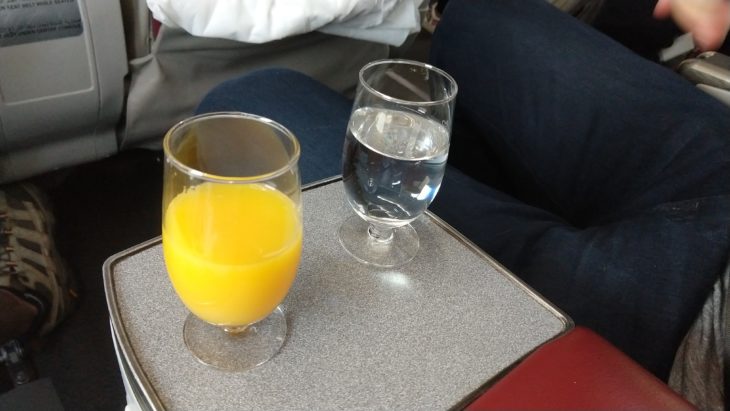 a glass of orange juice and a glass of water on a tray