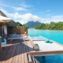 a deck with a pool and a hut on the water