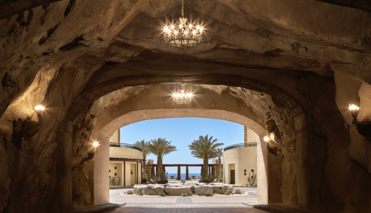 a large stone courtyard with palm trees and a chandelier