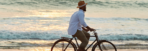 a man riding a bicycle on the beach