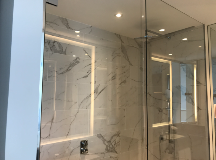 a glass shower with a marble wall