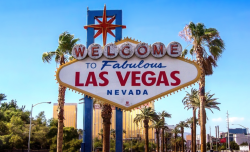 a sign with palm trees in front of it with Welcome to Fabulous Las Vegas sign in the background