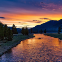 a river with trees and mountains in the background