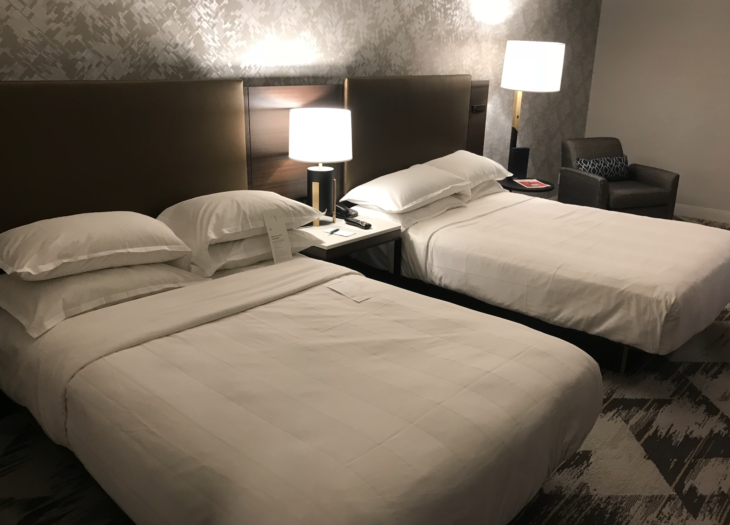 two beds with white sheets and pillows in a hotel room