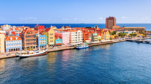 a colorful buildings along a body of water with Willemstad in the background
