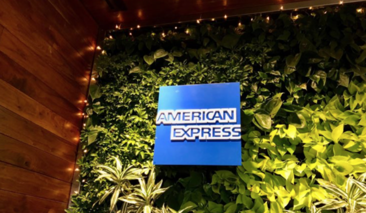 a blue sign on a wall of plants