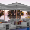 a white lounge chairs and umbrellas by a pool