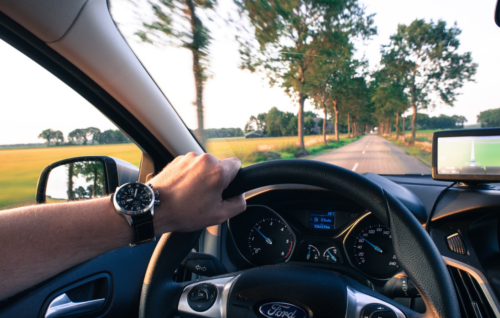 a hand on the steering wheel of a car