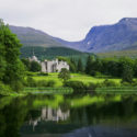 a lake with a castle and mountains in the background