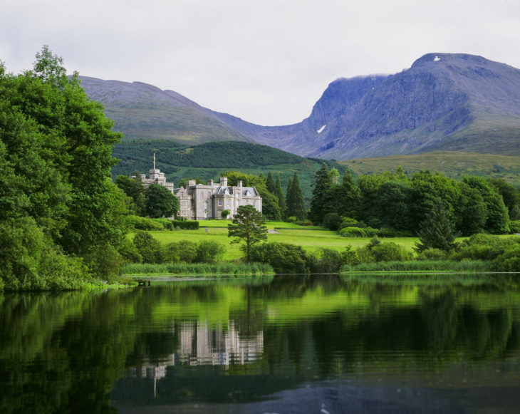 a lake with a castle and mountains in the background