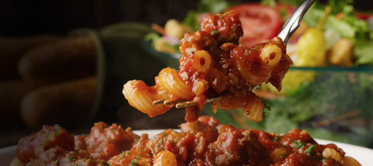 a fork holding pasta with meat and sauce