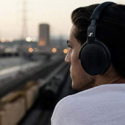 a man wearing headphones looking out to train tracks