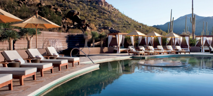 a pool with a waterfall and chairs