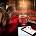 a person lying on a blanket next to a cup of coffee and a phone