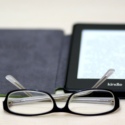 a pair of glasses next to a kindle