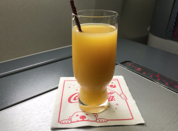 a glass of orange juice on a napkin