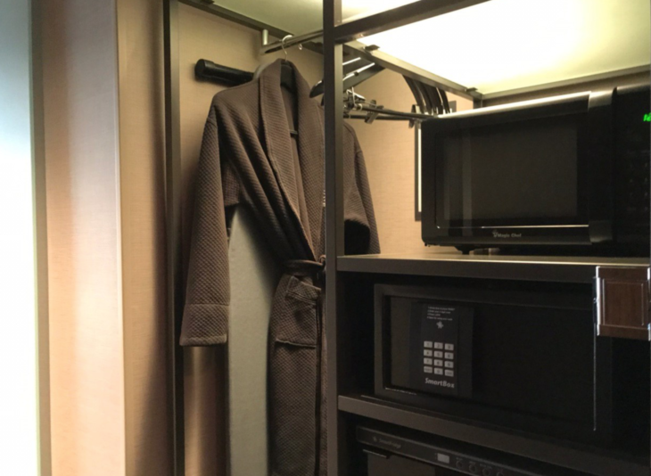 a brown robe on a swinger with a microwave and a shelf