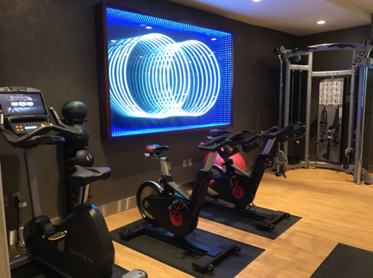 a room with exercise bikes and a large screen