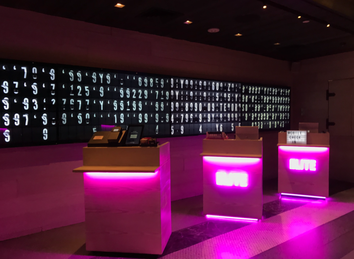 a room with pink lights and a large screen with numbers