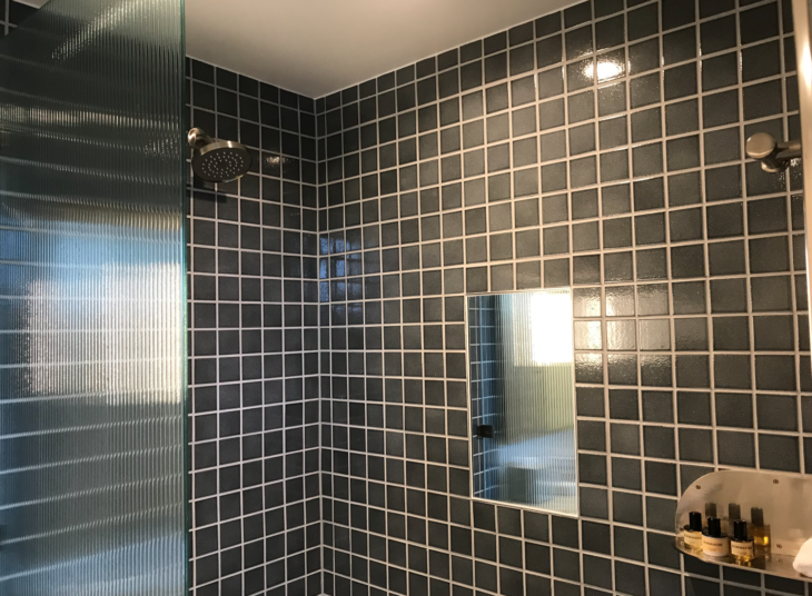 a shower with a mirror and a shower head