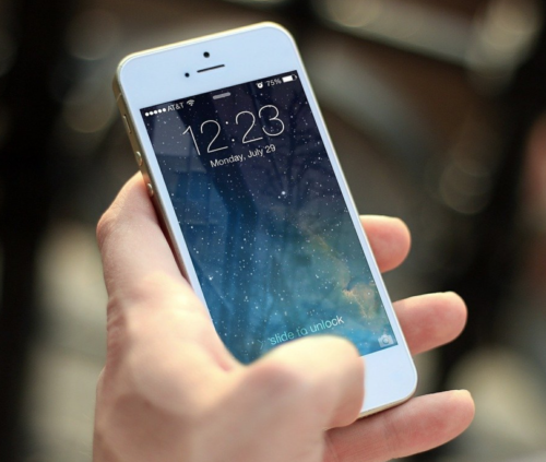 a hand holding a white cell phone