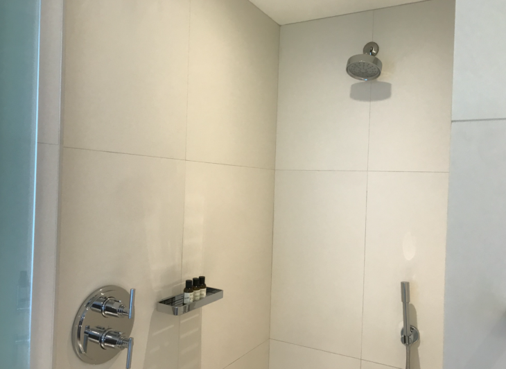 a shower with a shower head and a shelf
