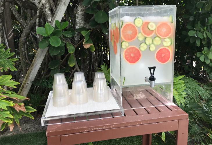 a water dispenser with fruit slices and cucumber on a table