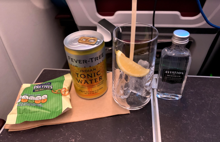 a glass of water with a lemon slice next to a can of soda