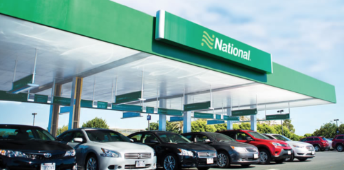 a car parking lot with cars parked in front of a green awning