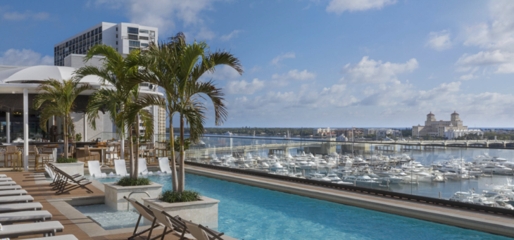 a pool with palm trees and a city in the background